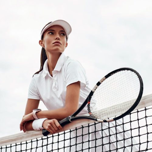 Young tennis player standing on a court and holding a racket